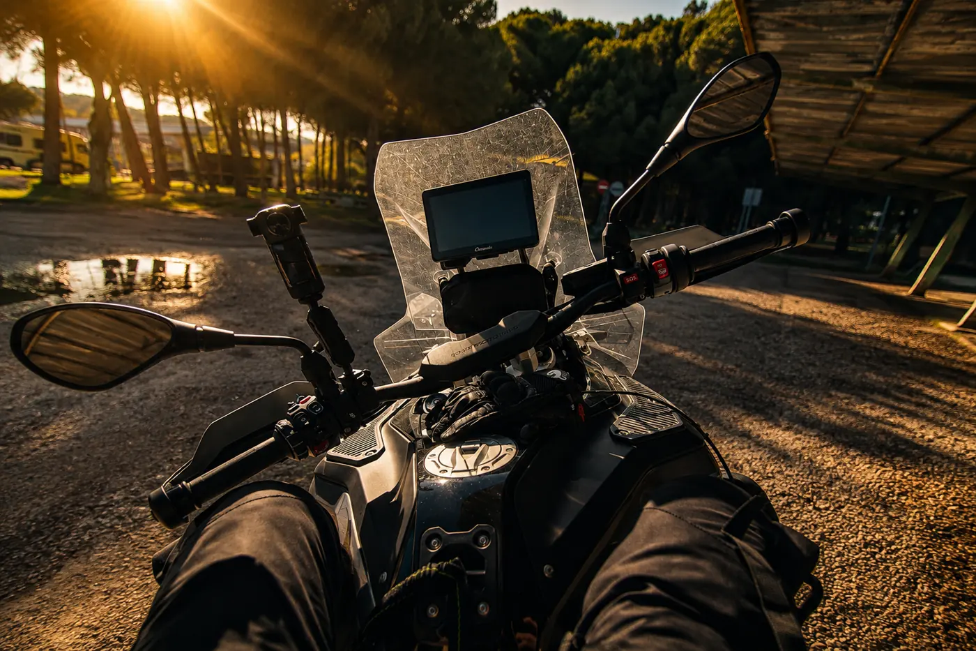 Jambes posées en avant sur les crashbars, moto à l'arrêt au soleil couchant